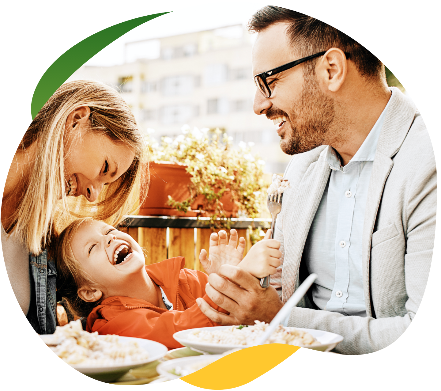 Young parents having a meal at the dining table, wearing their work clothes with their child sitting between them. They are laughing and having a good time together