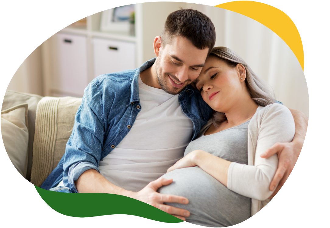 A pregnant woman suffering from bloating, sitting on the sofa with her eyes closed. Her partner comforts her and holds her in his arms