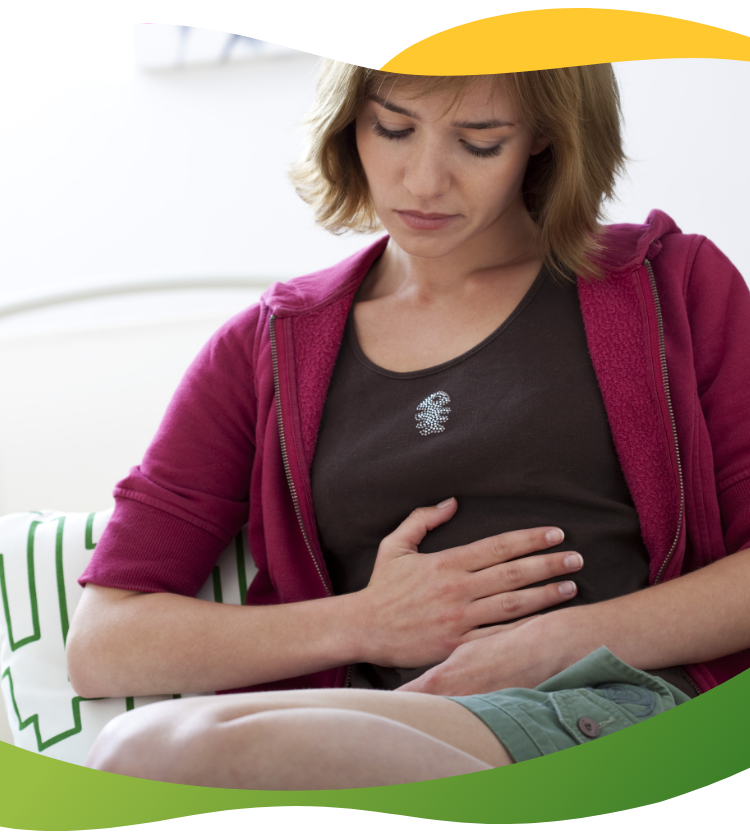 A young woman suffering from bloating and rubbing her belly with a pained face