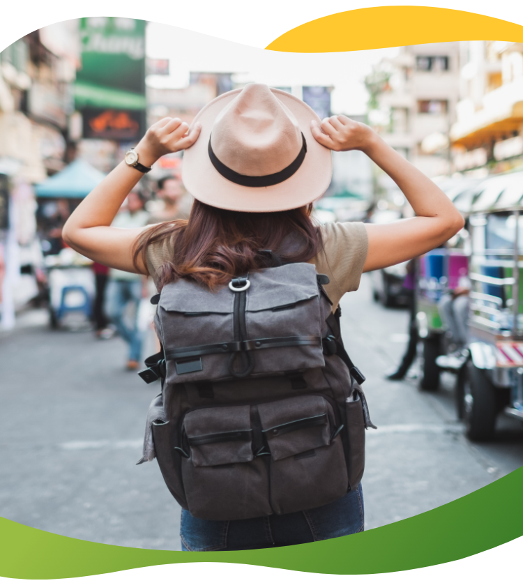 The back of a backpack tourist on the streets of Bangkok wearing a straw hat