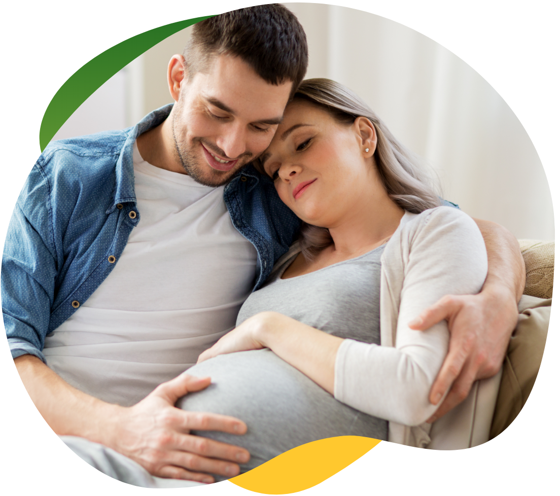 A pregnant woman suffering from bloating, sitting on the sofa with her eyes closed. Her partner comforts her and holds her in his arms