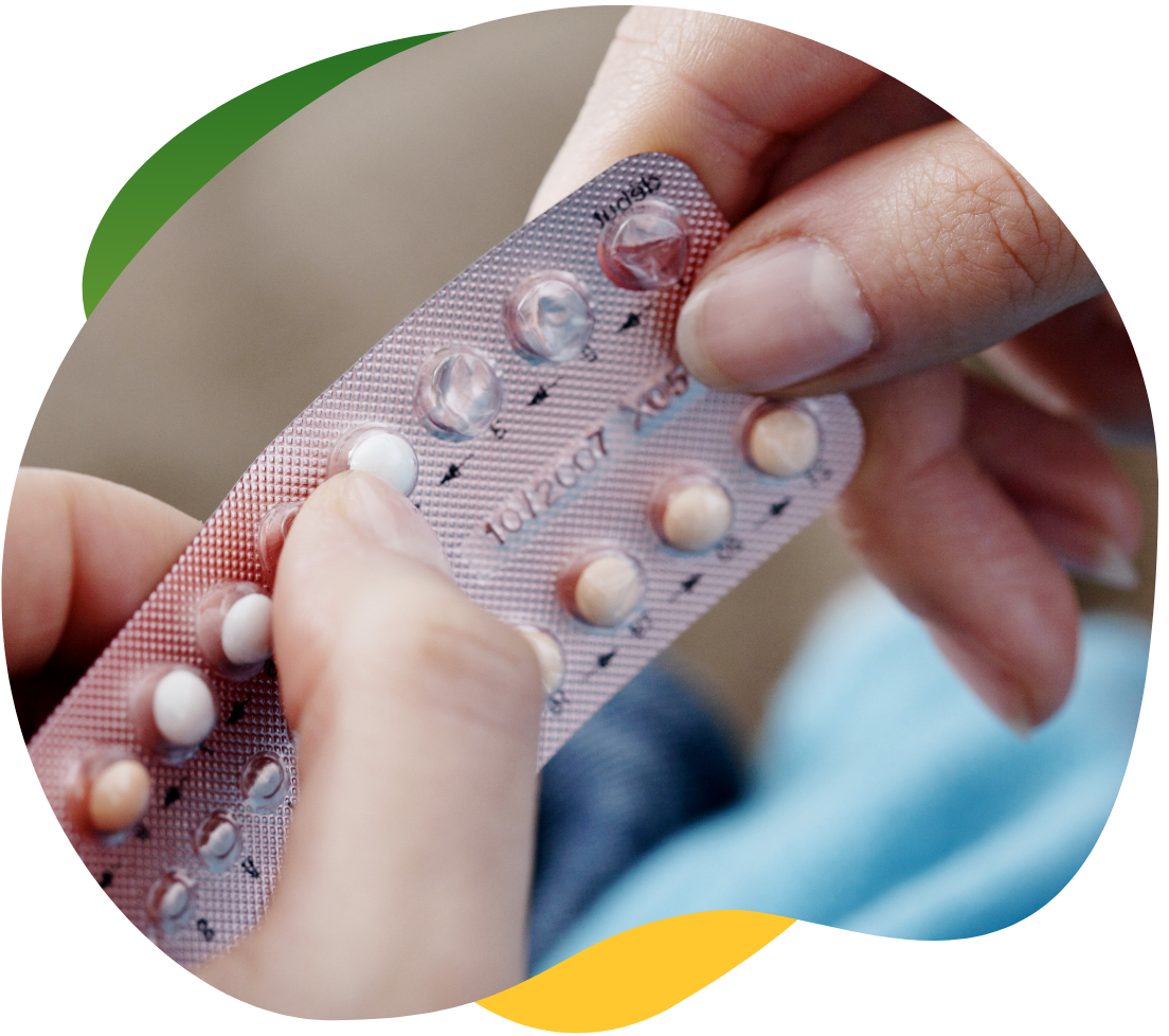 Woman’s hands pressing the birth control pill out of the package